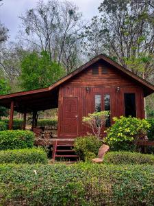 a small wooden cabin with a porch in a garden at Maingern Maithong Resort in Sara Buri