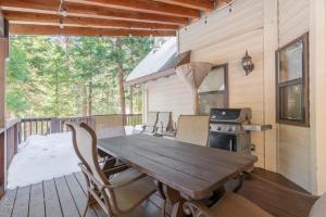 een houten tafel en stoelen op een terras met een fornuis bij Luxury Cabin: Hot Tub, Sauna, Pool and Sleeps 10 in Dorrington