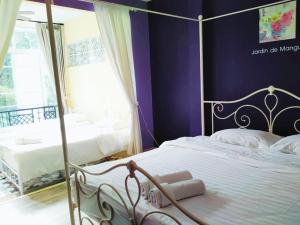 a bedroom with two beds with purple walls at Jardin De Mangue Pakchong in Pak Chong