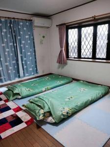 two beds in a room with two windows at Home Stay 北国分 in Ichikawa