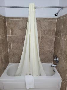 y baño con bañera y cortina de ducha. en Sands Motel, en Portales