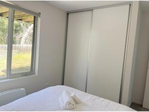 a bedroom with a bed with a window and two towels at Lovely room with private bathroom in Sandy Bay