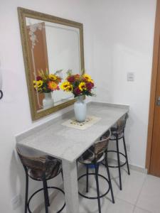 een tafel met een spiegel en een vaas met bloemen erop bij Flat Espetacular Recanto de Minas in São Lourenço
