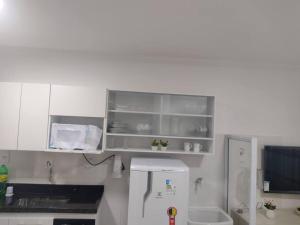 een keuken met witte kasten en een koelkast bij Flat Espetacular Recanto de Minas in São Lourenço