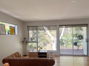 a living room with a couch and large windows at Lovely room with private bathroom in Sandy Bay