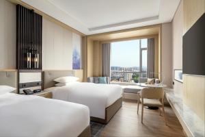 a hotel room with two beds and a desk at Courtyard by Marriott Shanwei Haifeng in Shanwei