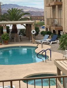 a swimming pool with two lounge chairs next to a building at 1st Floor Condo in the Desert w/ Pool, Spa & BBQ in Lake Havasu City
