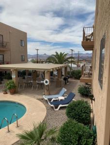 a patio with two lounge chairs and a pool at 1st Floor Condo in the Desert w/ Pool, Spa & BBQ in Lake Havasu City