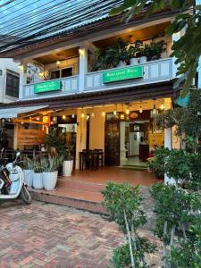 uma frente de loja com plantas e uma moto estacionada fora em Mano boutique sun shine em Luang Prabang