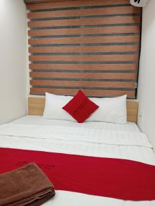 Una cama con una almohada roja encima. en Sophie hotel, en Hanói