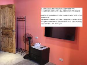 台東市的住宿－Peggy Home，一间设有红色墙壁、电视和风扇的客房