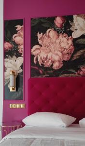 a bedroom with a pink wall with two pictures of flowers at L Suites The Writer's House in Gythio
