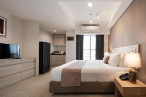 バンコクにあるアスピラ レジデンス ルアムルディーのベッドとテレビが備わるホテルルームです。