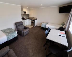 een hotelkamer met een bed en een tafel en stoelen bij BK's Pohutukawa Lodge in Whangarei