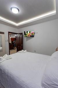 a bedroom with a white bed with a tv on the wall at OOferta de ultimo minuto A 15 minutos del Aeropuerto SPS in San Pedro Sula