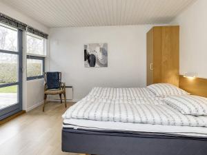 a bedroom with a bed and a chair and a window at Four-Bedroom Holiday home in Væggerløse 22 in Marielyst