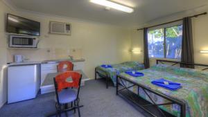 a small room with a bed and a table and chairs at Barcaldine Caravan Park in Barcaldine