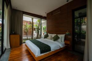 a bedroom with a large bed and a large window at Grün Canggu Garden in Canggu