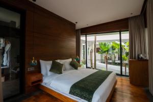 a bedroom with a bed and a large window at Grün Canggu Garden in Canggu