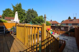 una terraza de madera con una valla amarilla y una sombrilla en 3 bedrooms Sleeps 8 Self Catering House Near Norwich City Centre And UEA, en Earlham