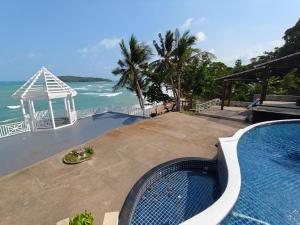 a swimming pool next to a beach with the ocean at Bhundhari Resort & Villas Samui in Chaweng