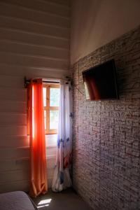Habitación con ventana con cortinas y TV. en Villa Raynell, en Constanza
