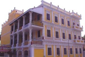 un gran edificio blanco y amarillo con muchas ventanas en Hotel Soorya Inn, en Pondicherry