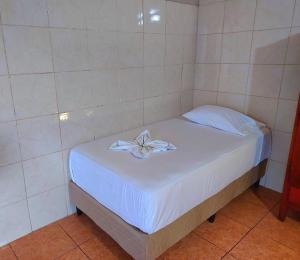 a white bed with a flower on top of it at Hostel del Pacífico in Puntarenas