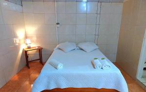 Un pequeño dormitorio con una cama blanca con toallas. en Hostel del Pacífico en Puntarenas