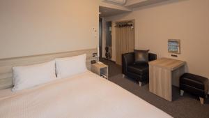 Hotel Route Inn Grand Wakayama Eki Higashiguchi في واكاياما: غرفه فندقيه بسرير وكرسي