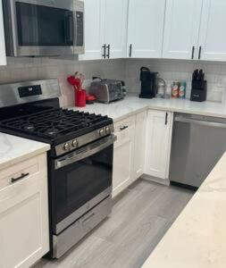 a kitchen with white cabinets and a stove top oven at Lux w/ 3 bd King & 3ba Mins to Dwntwn Houston Tx! in Houston