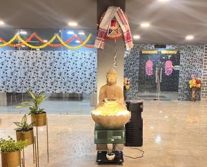 eine Statue eines Buddha in einem Raum mit Pflanzen in der Unterkunft JD Grand Inn in Guwahati