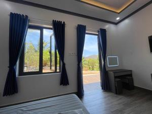 una camera da letto con finestra e tende blu di Bàu Trắng Farmstay a Ấp Thiẹn Ái
