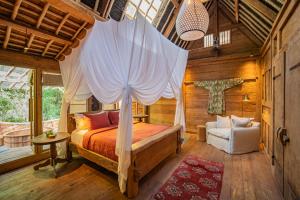 a bedroom with a bed with a canopy at Bambu Indah in Ubud