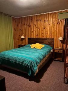 1 dormitorio con 1 cama con manta verde y paredes de madera en Bosque Mágico Oasis La Campana Hijuelas, en Ocoa