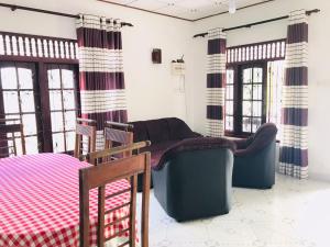 ein Wohnzimmer mit Stühlen, einem Sofa und Fenstern in der Unterkunft Family Villa Mirissa in Mirissa