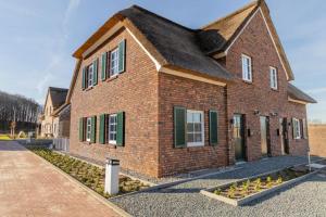 a brick house with green shutters on a street at Villa Heimathafen Rügen - Luxus gepaart mit Wellness in Lohme