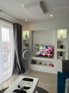 een woonkamer met een flatscreen-tv aan de muur bij The Coffee Residences- 3 Bedroom Apartments-4km to JKIA, 7km to CBD in Nairobi