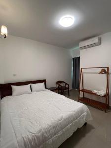 um quarto com uma grande cama branca e uma cadeira em D32 Homestay near airport Behind Brown coffee airport em Phnom Penh