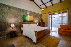 a bedroom with a bed and a couch and a window at Arsulana Eco Lodge & Spa in Ginigathena