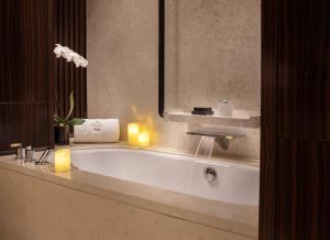 uma casa de banho com uma banheira com 2 velas e 2 velas em Beijing Hotel NUO Forbidden City em Pequim