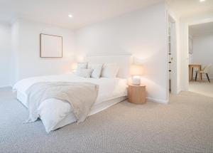 a white bedroom with a large bed and a table at Elegance and Style in Wagga Wagga