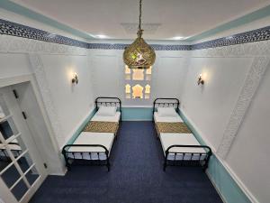 Habitación con 4 camas y lámpara de araña. en Guest house Gula en Samarcanda