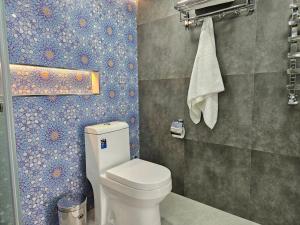 a bathroom with a toilet and a tile wall at Guest house Gula in Samarkand