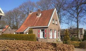 una casa con techo marrón y persianas rojas en Carpe Diem, en Ommen