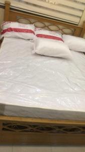 uma cama com lençóis brancos e almofadas vermelhas e brancas em Taiky em Um Qeis