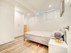 a white bedroom with a bed and a table at Cozy & Luxurious 3-BR condo (4min to metro) in Montreal