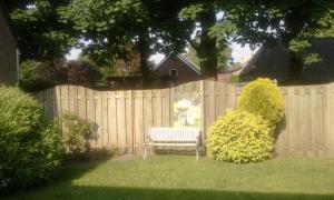 a wooden fence with a bench in a yard at Carpe Diem in Ommen