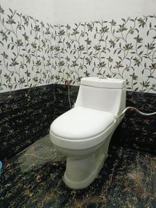 a white toilet in a bathroom with floral wallpaper at Siya home stay in Faizābād