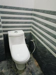 a white toilet in a bathroom with black tiles at Siya home stay in Faizābād